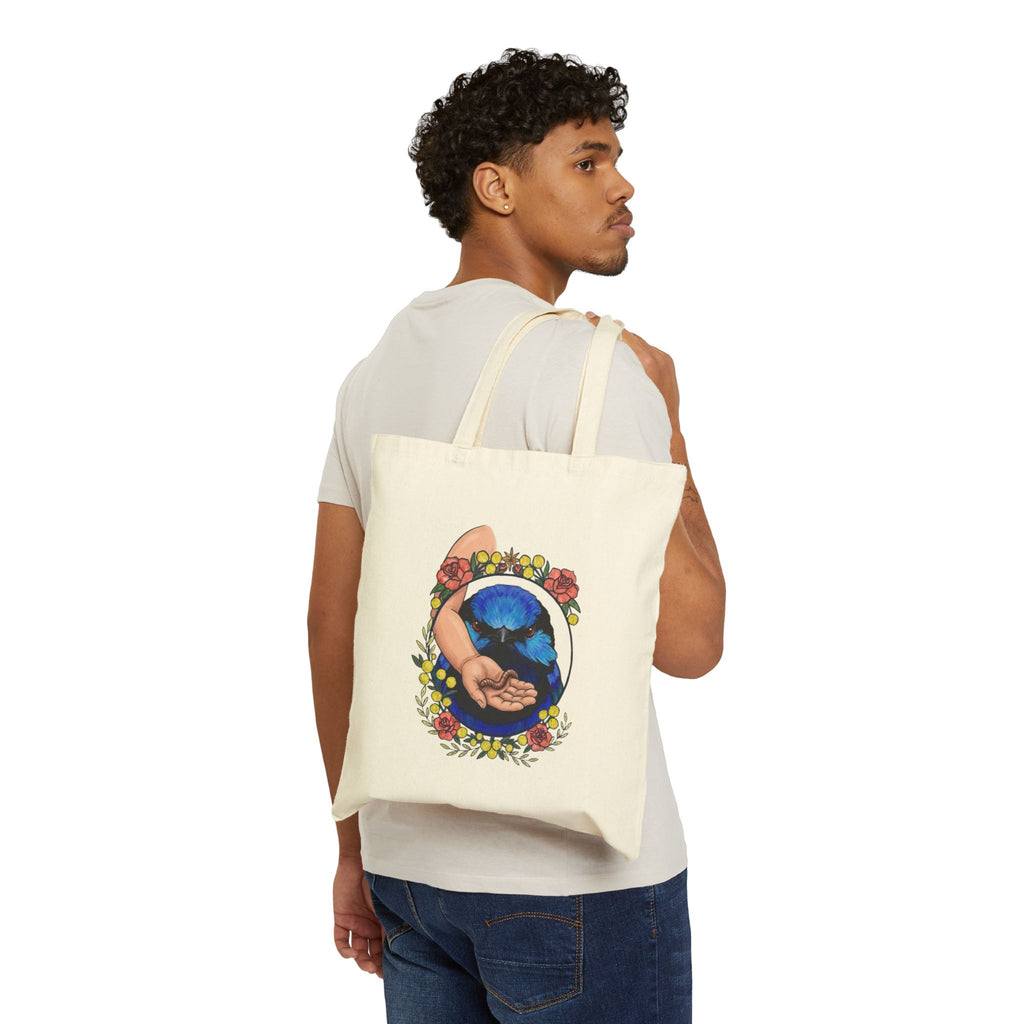 Natural canvas tote bag worn by a person, blue-toned hand-and-grubs graphic