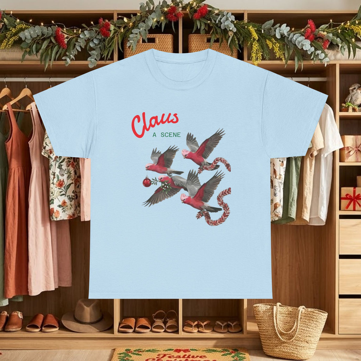 Light blue Christmas graphic tee with “Claus” text and red flying bird scene