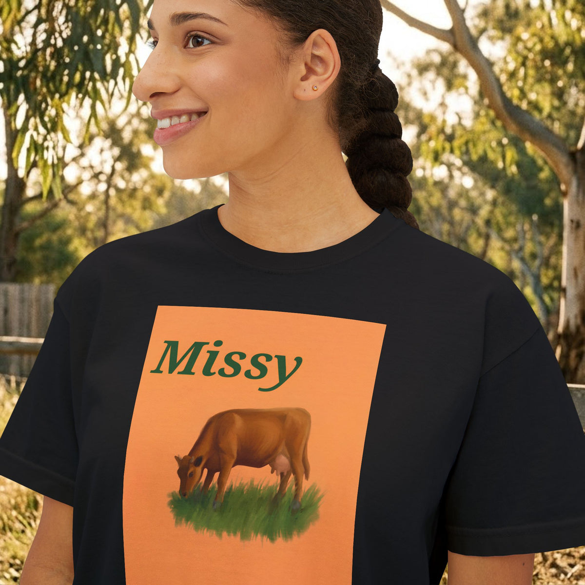 Black boxy T-shirt close-up of “Missy” cow graphic on an orange square.