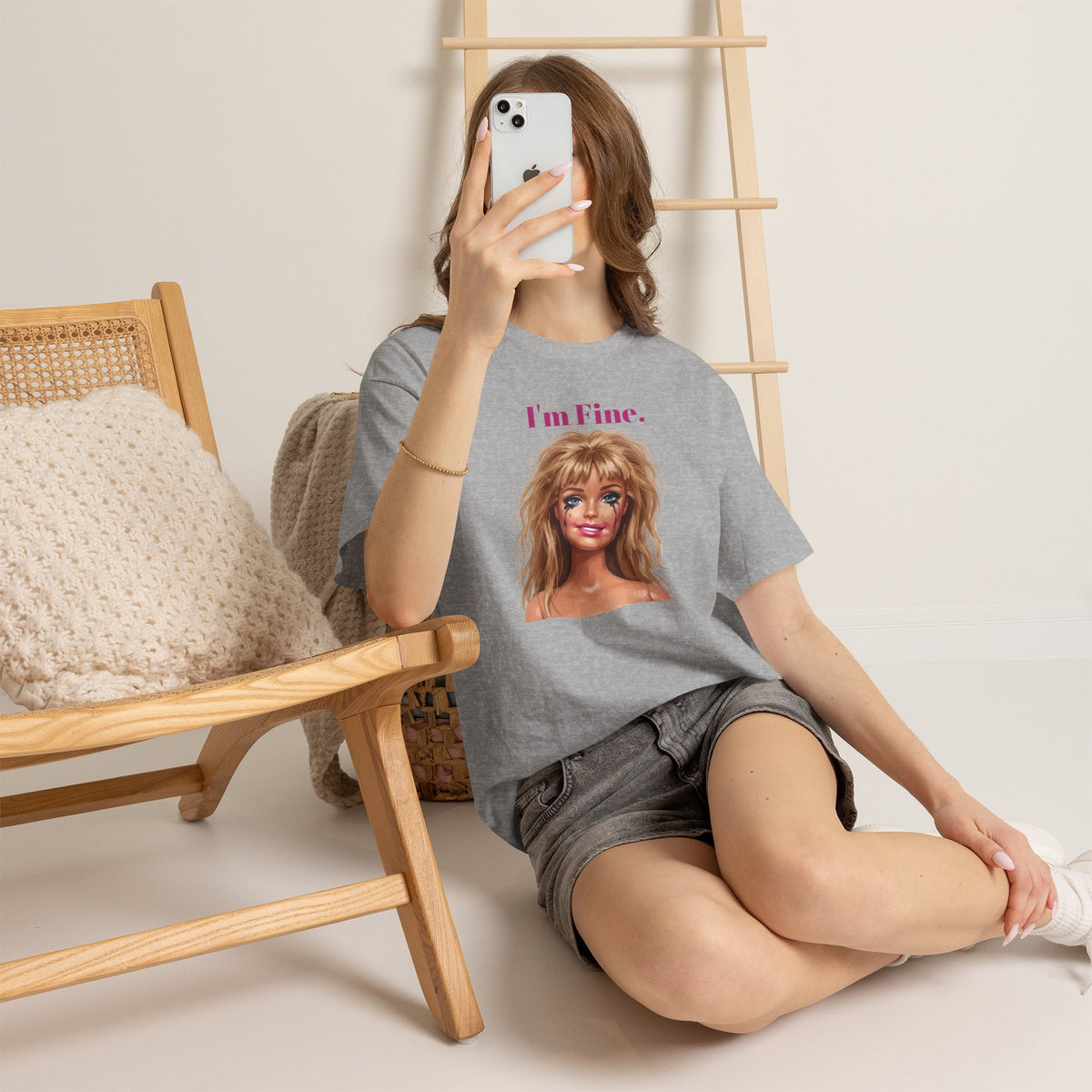 Heather gray crewneck T-shirt with doll face graphic and “I’m Fine.” text, casual seated