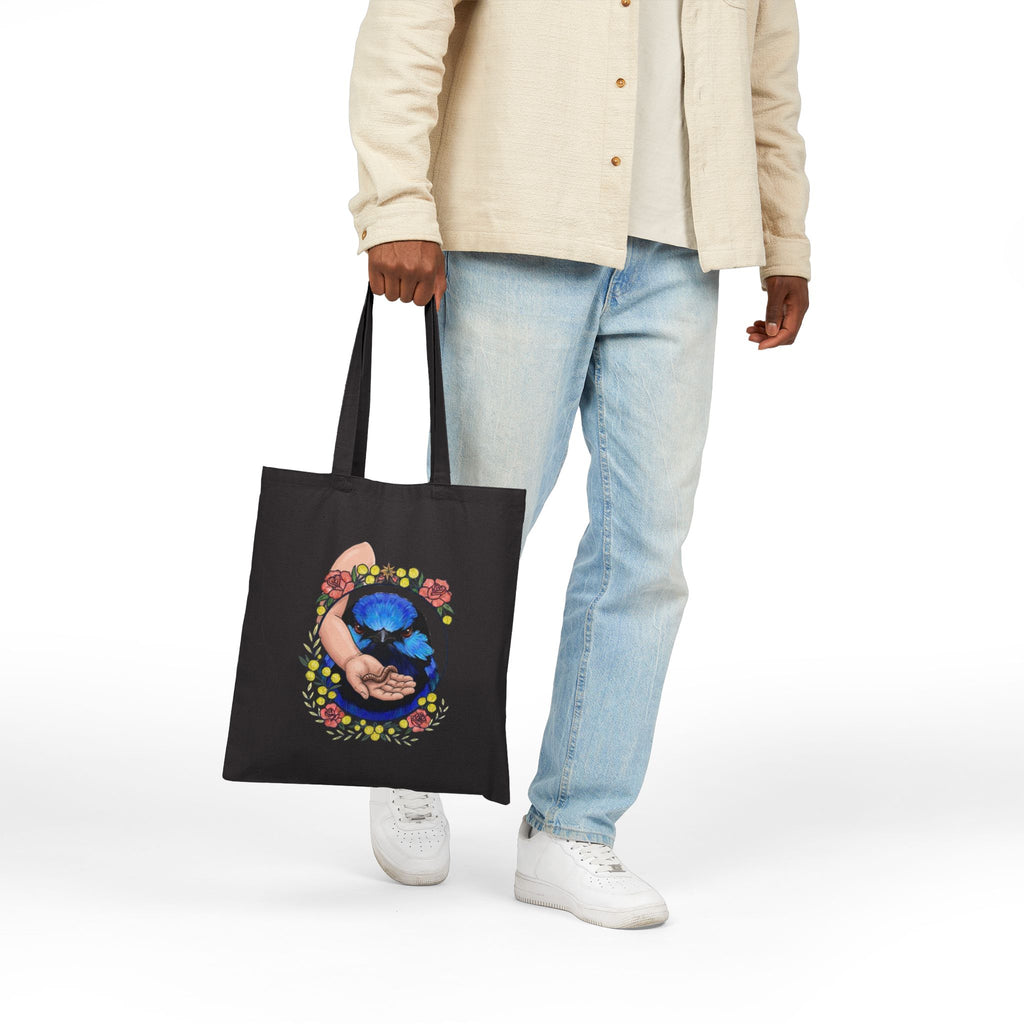 Black canvas tote bag with blue-green circular hand-holding-grubs artwork
