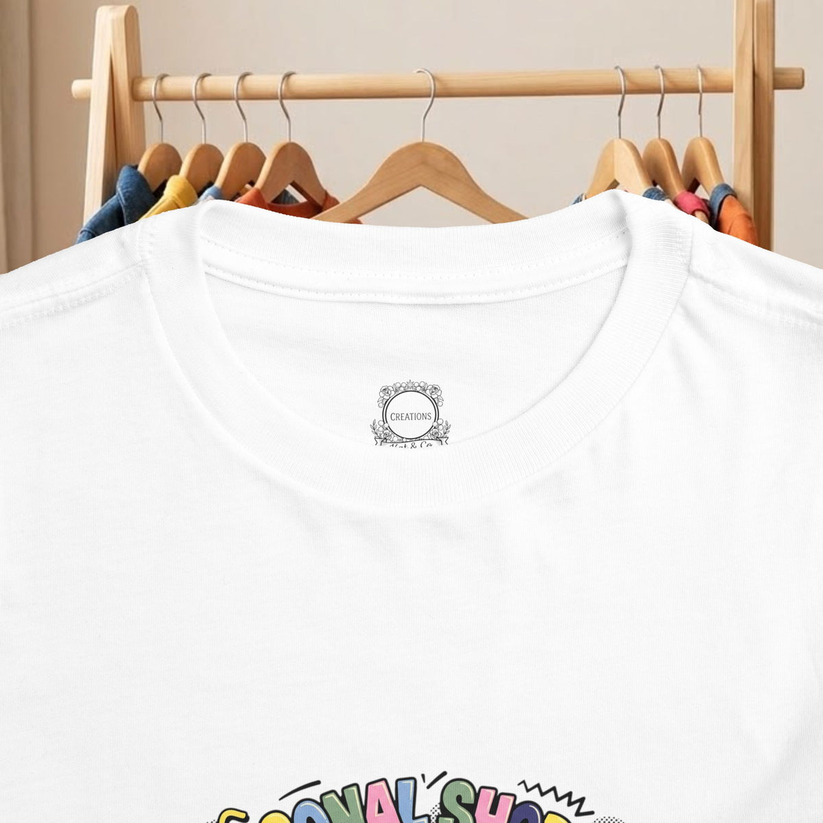 White toddler tee close-up of round neckline badge and partial front graphic