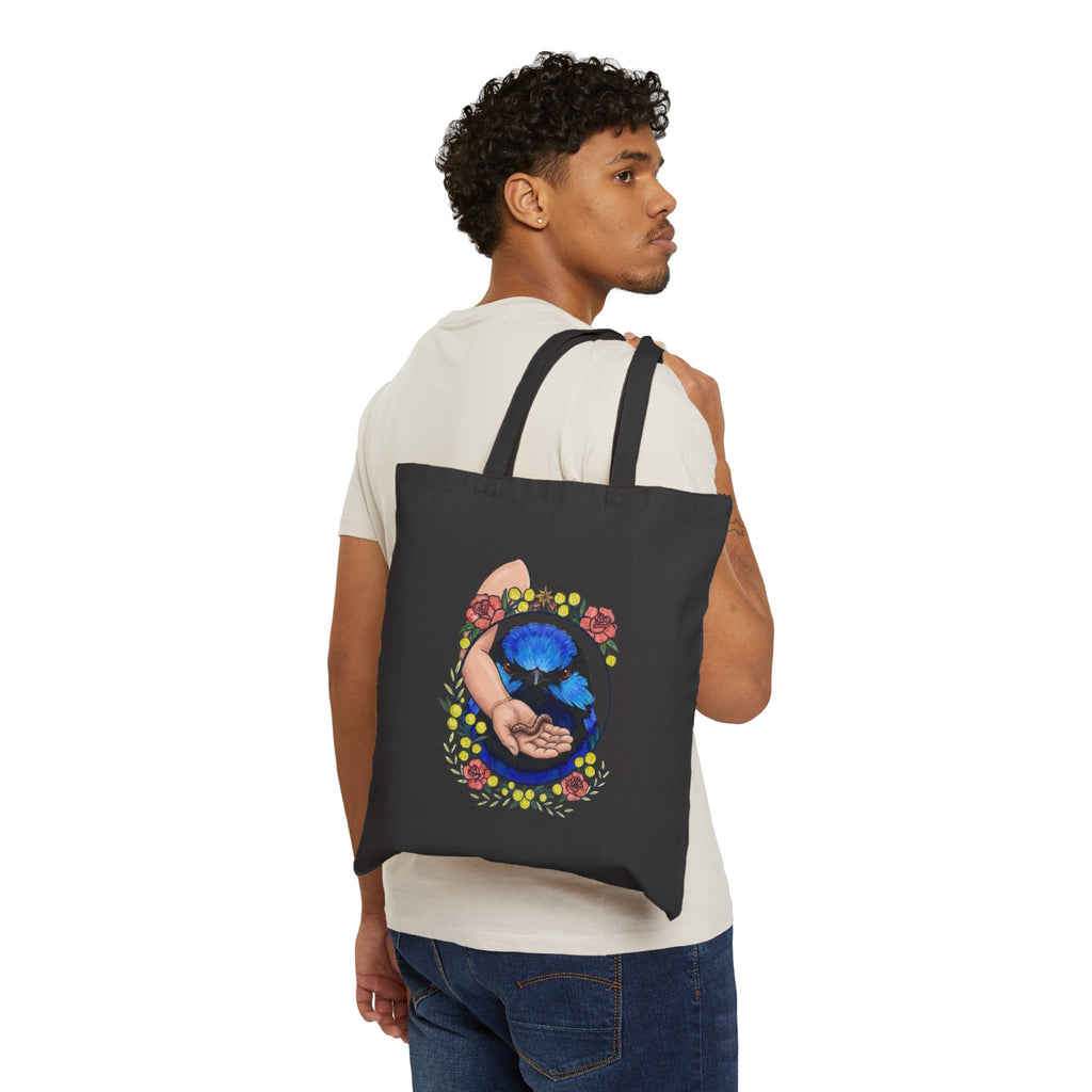 Black canvas tote bag worn by a person, blue-toned hand-and-grubs graphic
