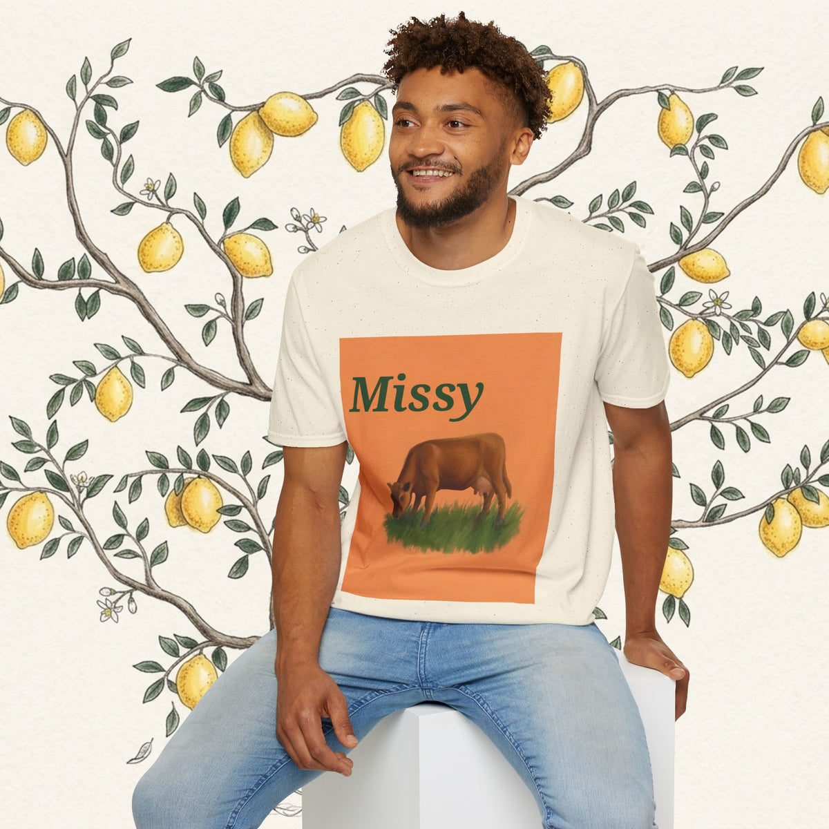 White crew-neck t-shirt with orange “Missy” grazing cow graphic centered on chest.