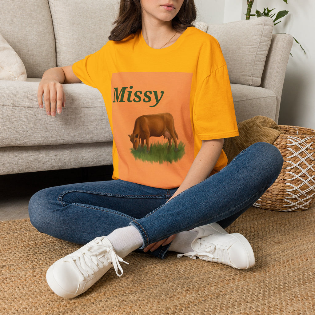 Orange Missy cow graphic T-shirt on model sitting with blue jeans