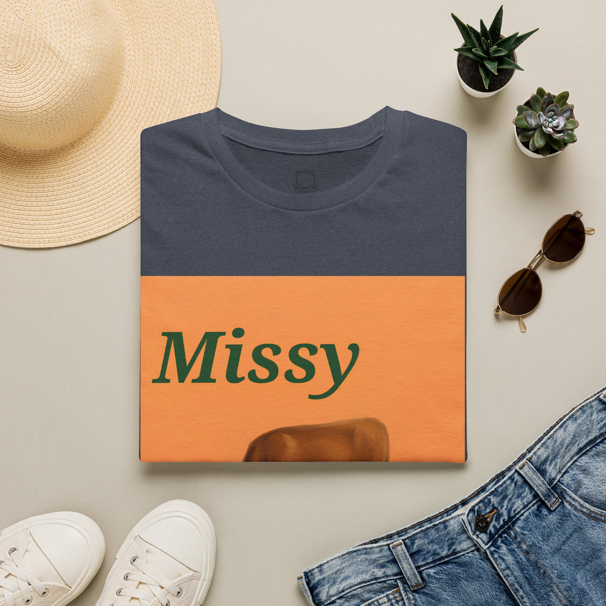 Navy folded t-shirt with orange 'Missy' cow graphic