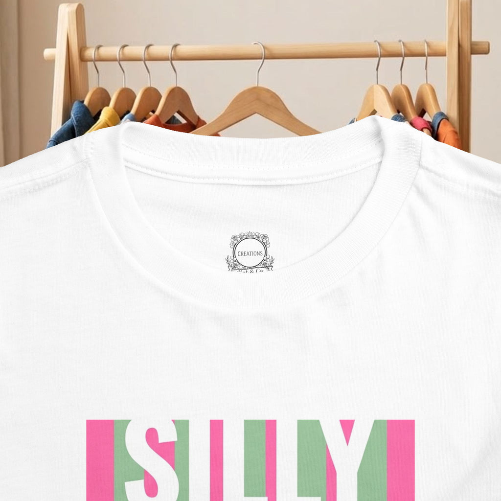 White toddler tee close-up showing 'SILLY' print and small neck label
