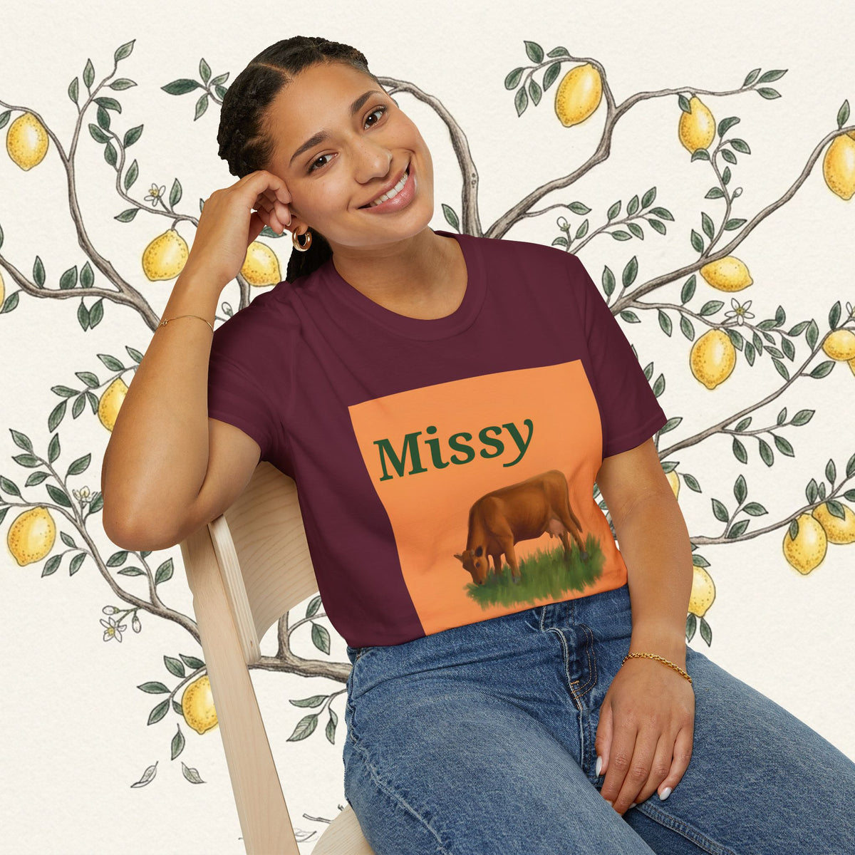 Maroon crewneck T-shirt on model with square orange graphic panel and brown grazing cow