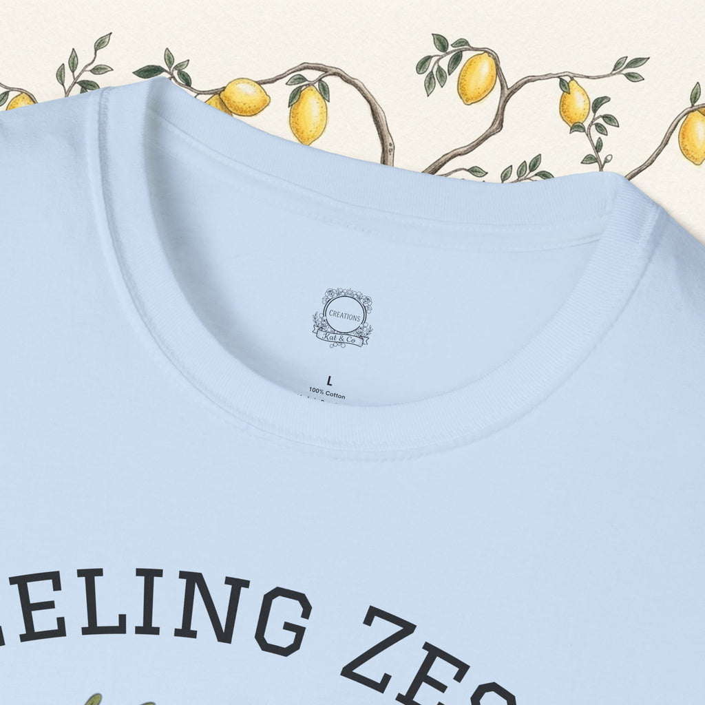Light blue crewneck graphic tee, showing partial "FEELING ZESTY" text on front