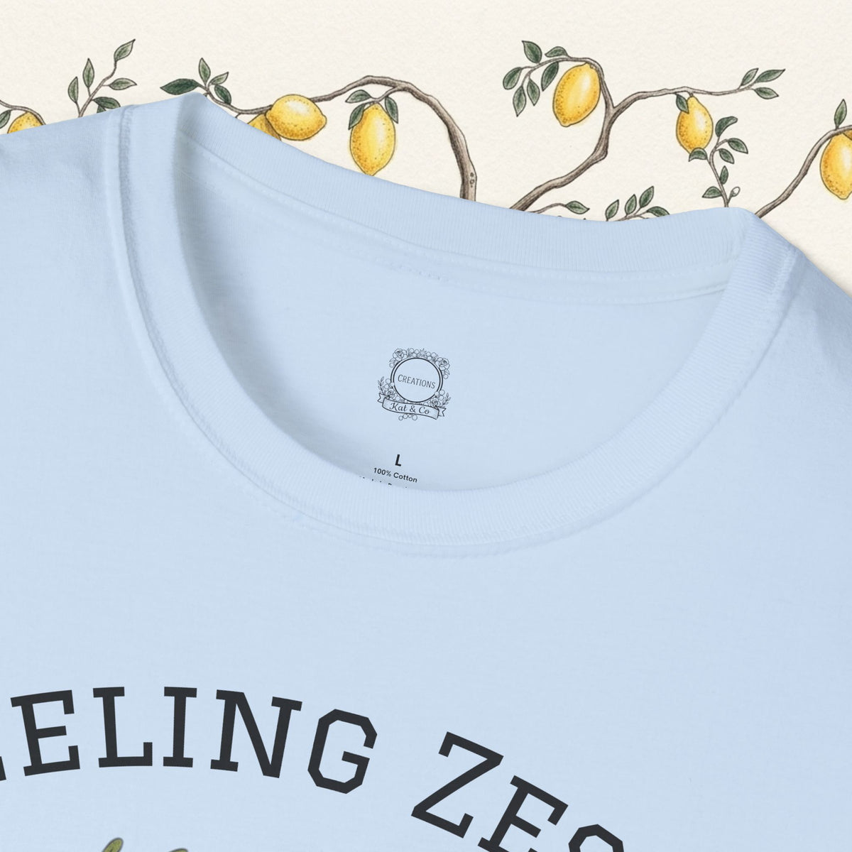 Light blue crewneck graphic tee, showing partial "FEELING ZESTY" text on front