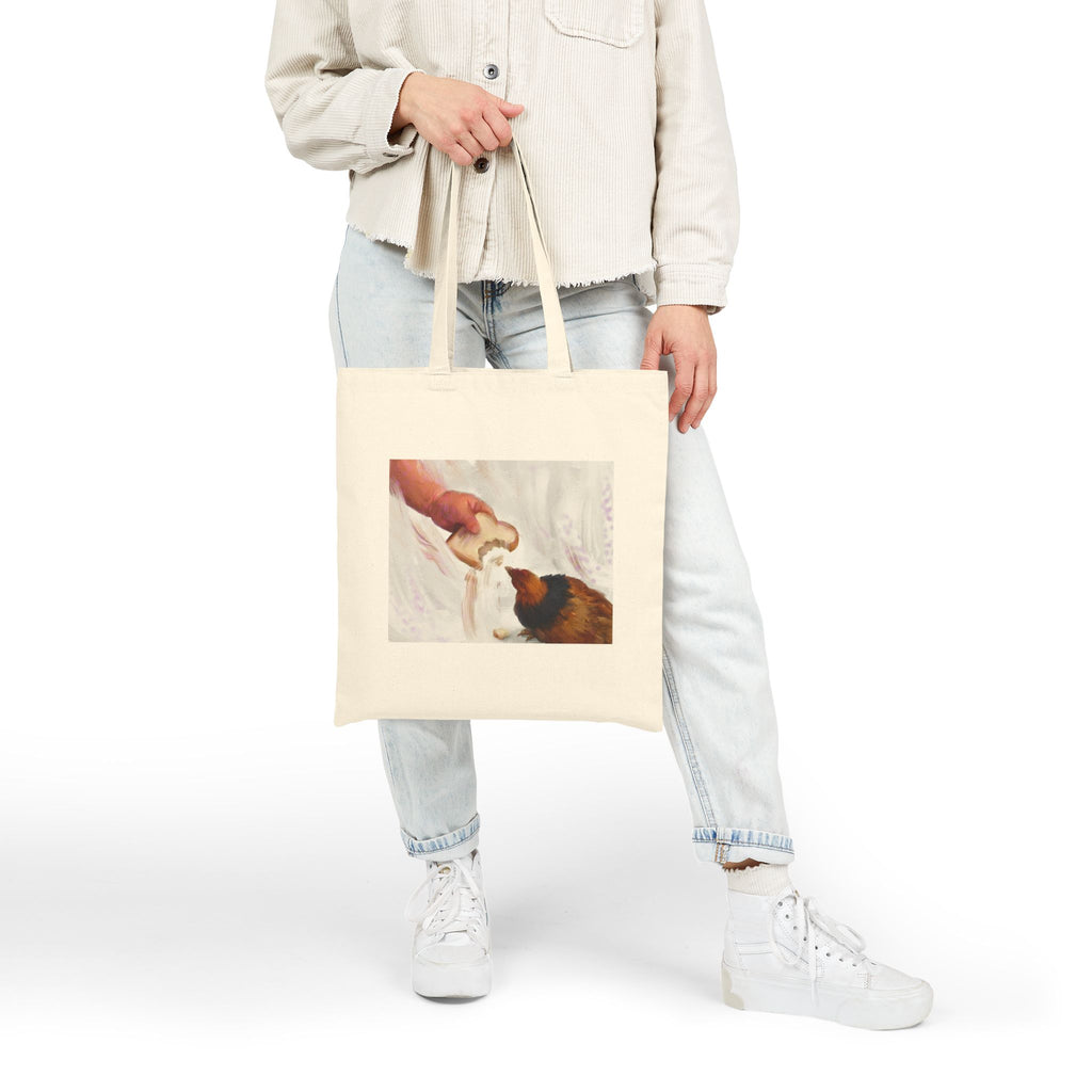 Natural canvas tote bag with vintage hen feeding illustration, front view while held.