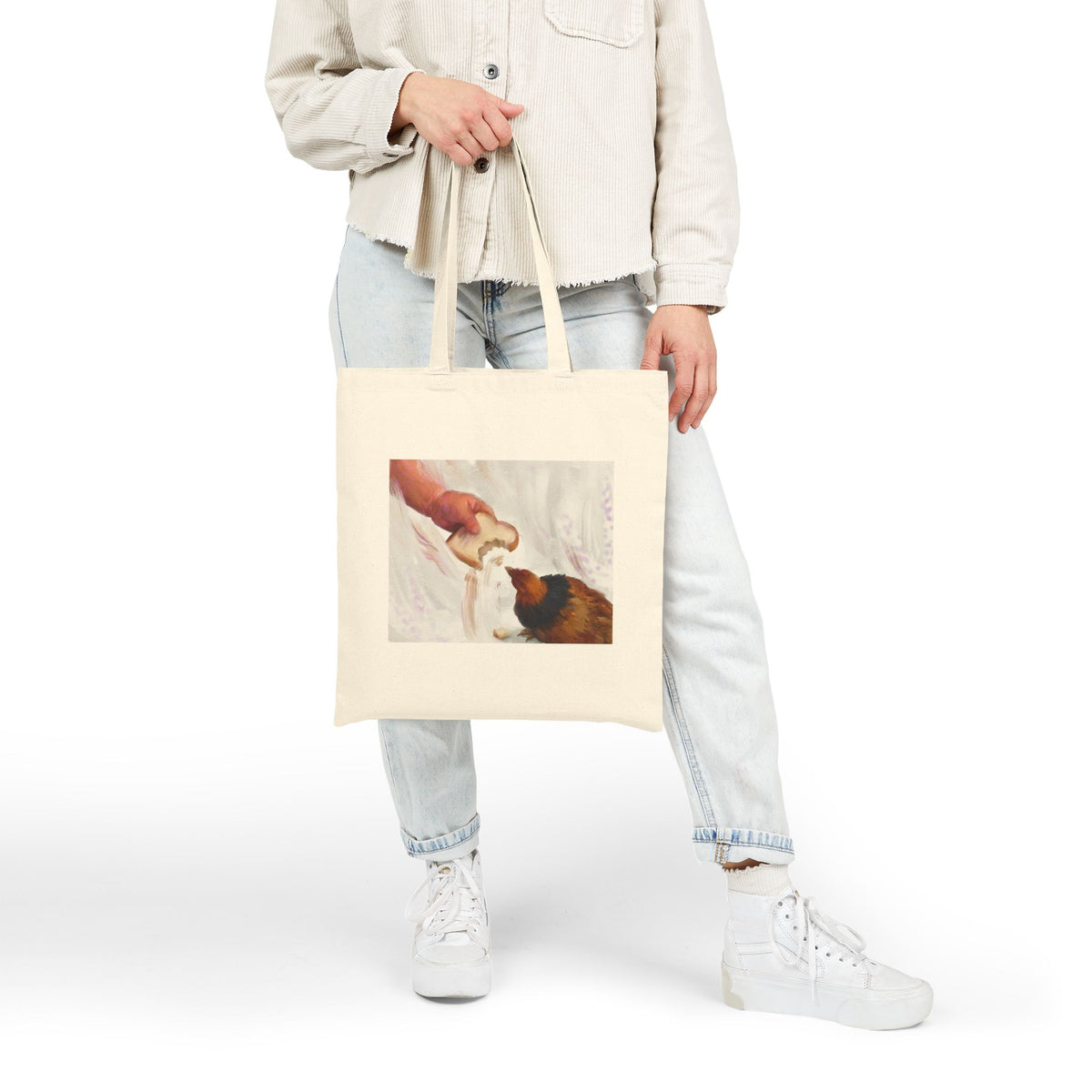 Natural canvas tote bag with vintage hen feeding illustration, front view while held.