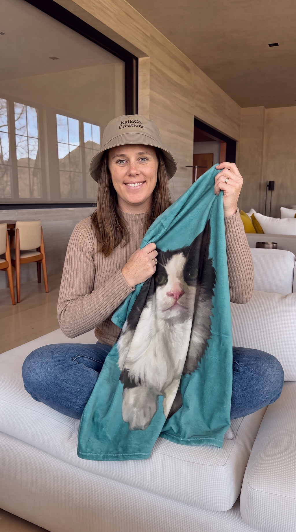 Personalized pet photo blanket on person’s lap, teal plush with black-and-white cat portrait