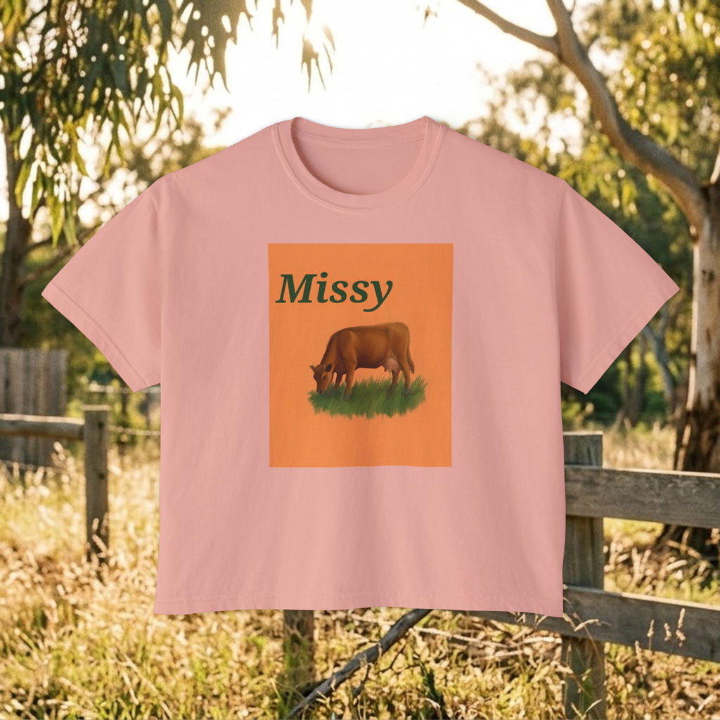 Women’s boxy tee in peach pink with “Missy” cow illustration graphic on the front.