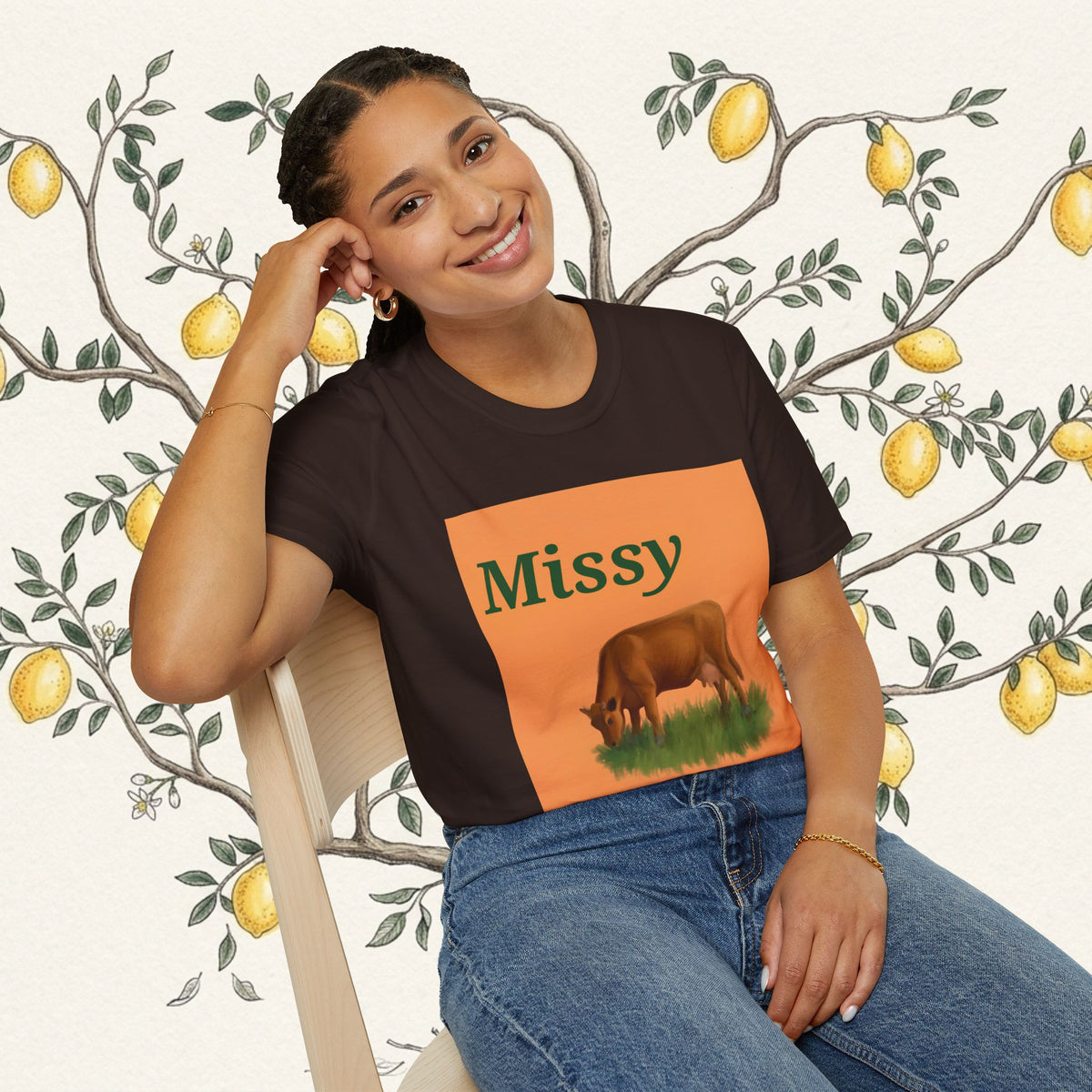 Dark brown cow graphic T-shirt with orange square print, seated model pose