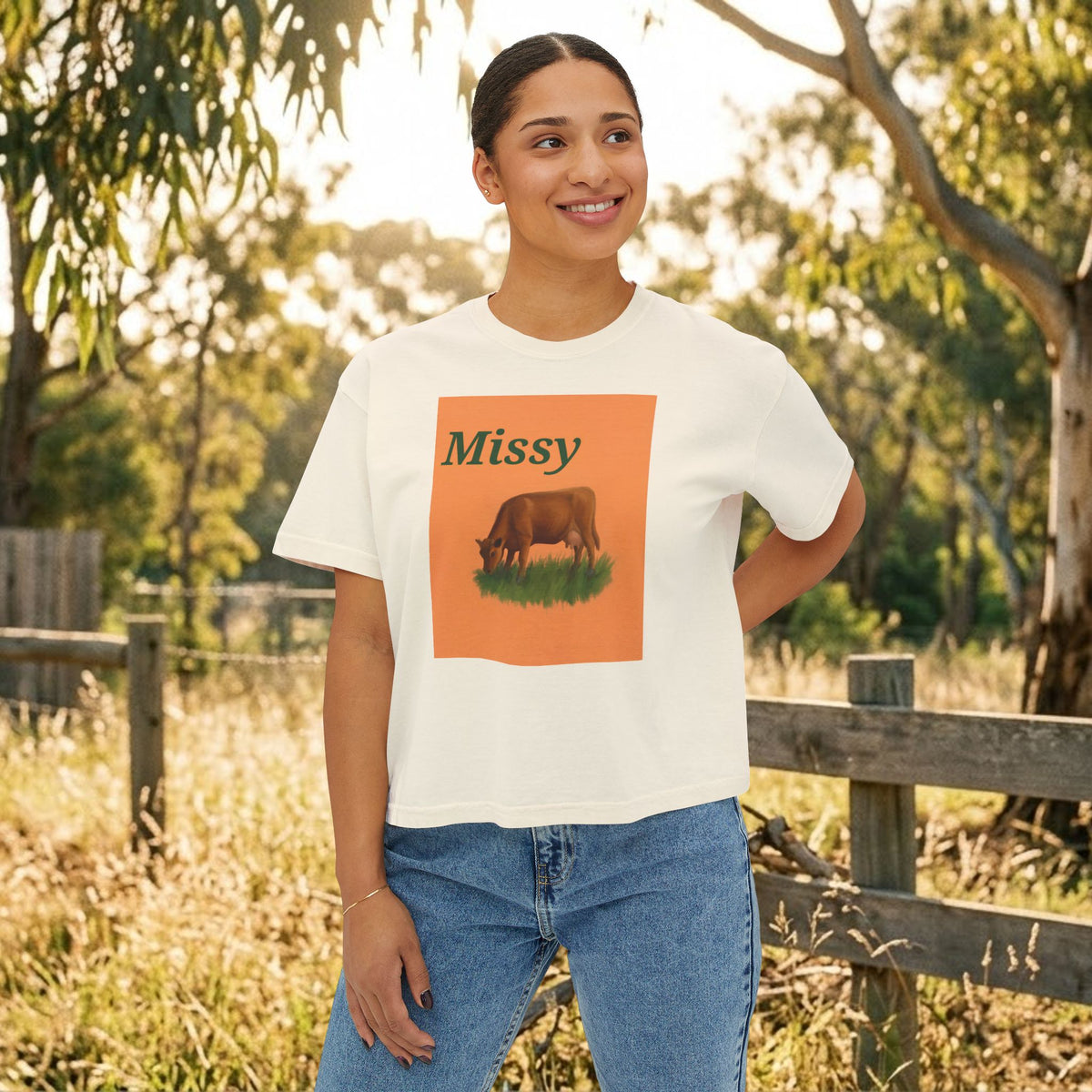 Cream boxy T-shirt worn by model, orange cow graphic with “Missy” on front.