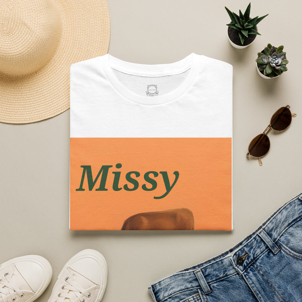 White crewneck T-shirt with orange “Missy” grazing cow graphic panel