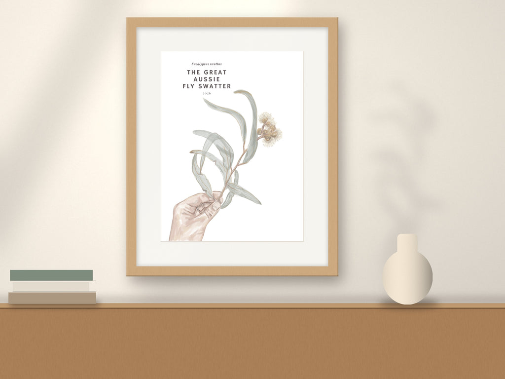 Wood-framed eucalyptus wall art print featuring hand holding eucalyptus leaves and flowers