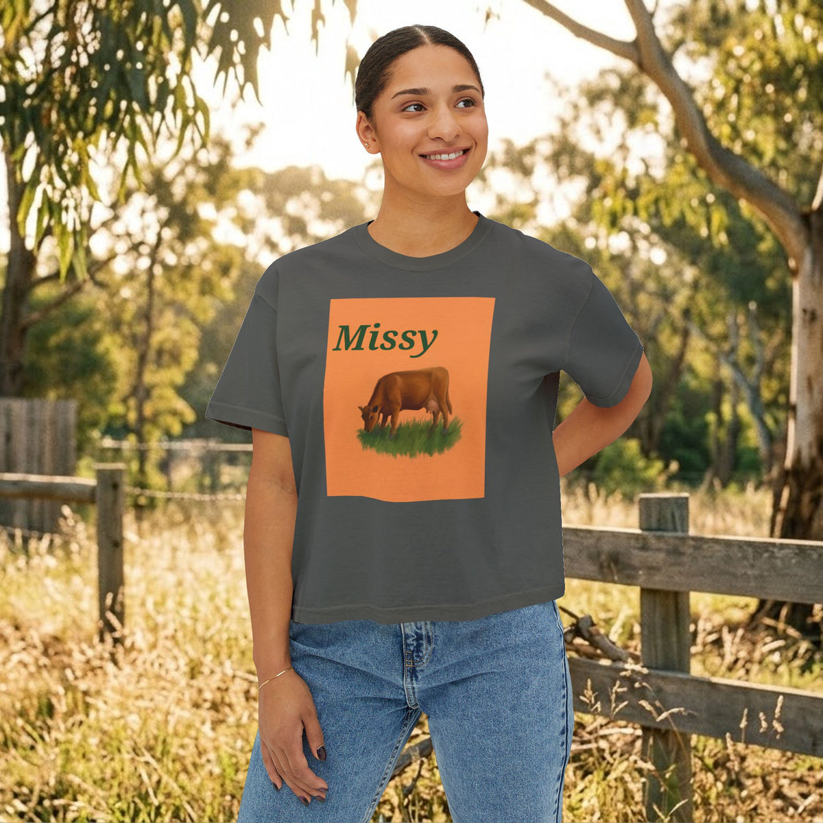 Dark gray boxy T-shirt worn by model, orange cow graphic with “Missy” on front.