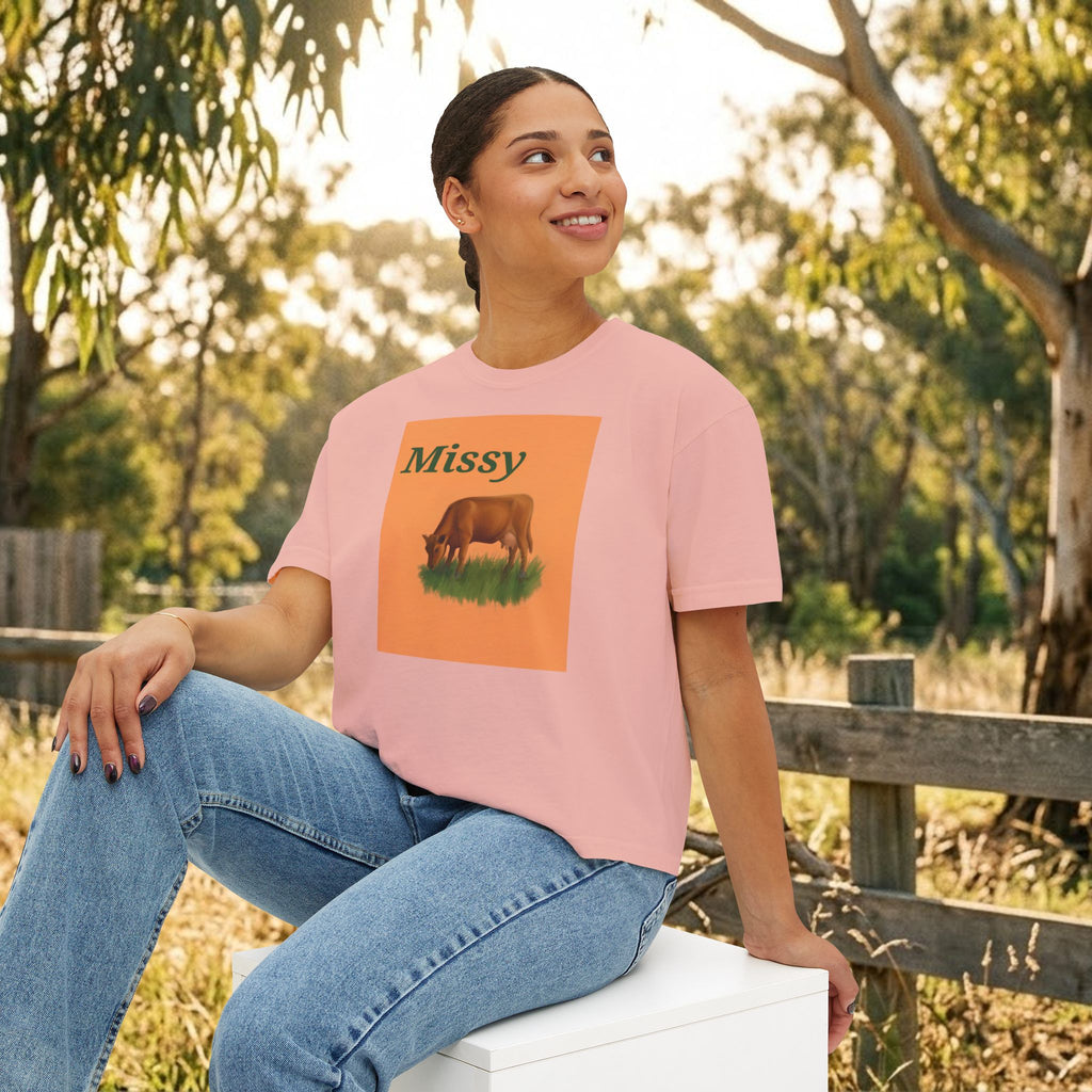Women’s boxy tee in peach pink with “Missy” cow illustration graphic on the front.