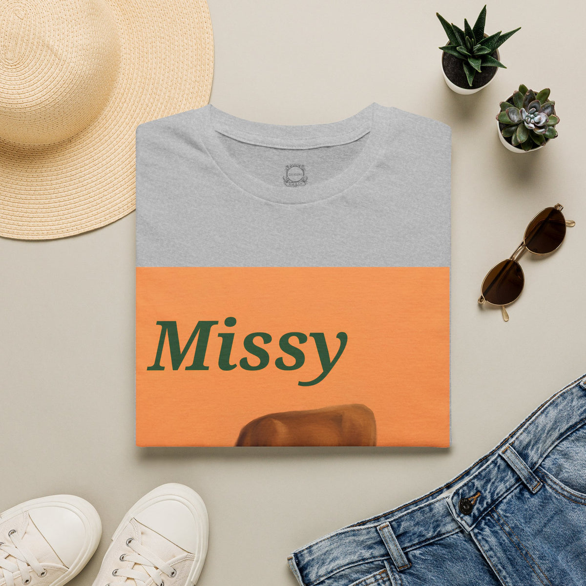 Heather grey T-shirt flat lay with orange square cow graphic and “Missy” text