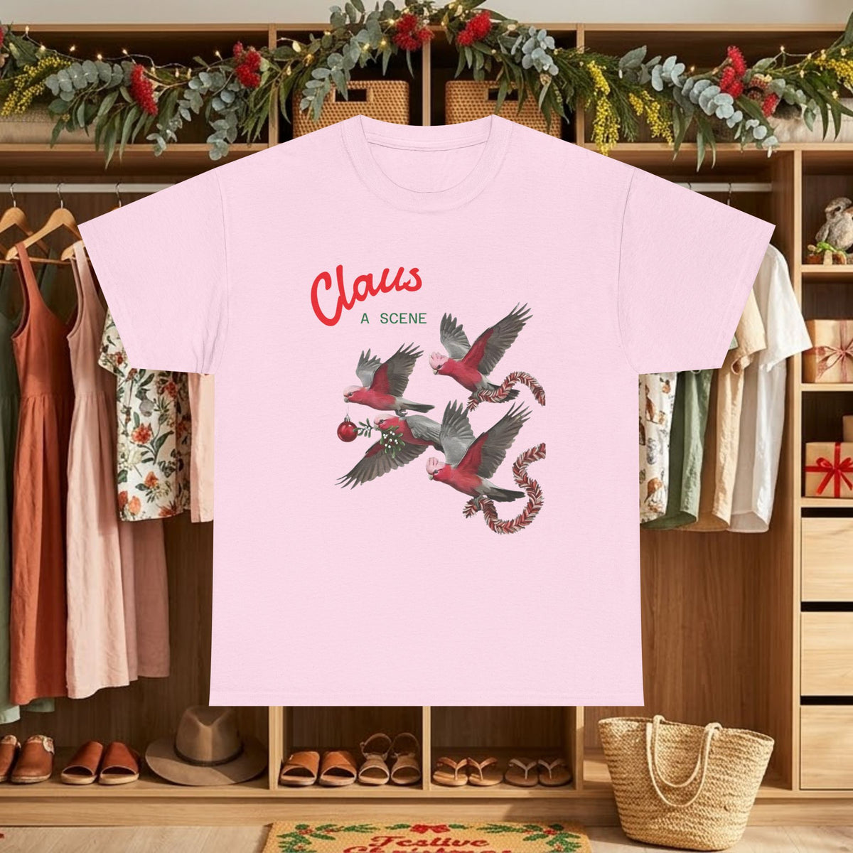 Pink Christmas graphic tee with “Claus” text and red flying bird scene