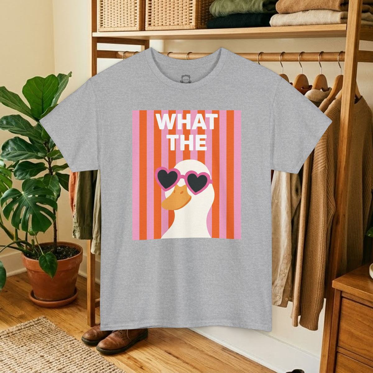 Light gray crewneck T-shirt with “WHAT THE” duck graphic and heart sunglasses
